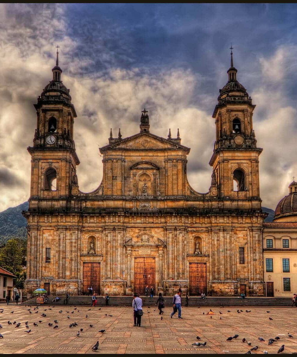 This is the main Cathedral in Bogota, Colombia, called Catedral Primada. It is in the East side of the Plaza de Bolivar.

ISO 100, 15mm, f9, (1/800, 1/200, 1/50) handheld. HDR processing in Photomatix using Details Enhancer and Light mode. Imagenomics Noiseware, in PS Smart Sharpen, and Freaky Details. The warm colors came from Nik Color Efex  Skylight and Indian Summer filters. I colored the sky blue using Nik Viveza 2 as Photomatix had produced the typical darkish desaturated blue. It often does this, note that the shirts of the people walking in the plaza are actually white.